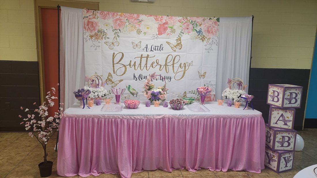 Butterfly-themed treat table with pink skirting, candy dishes, and floral hoop centerpieces